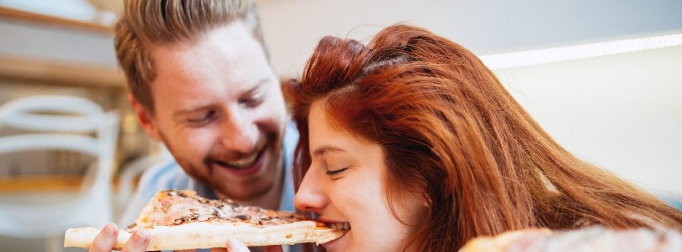 Couple sharing pizza and eating