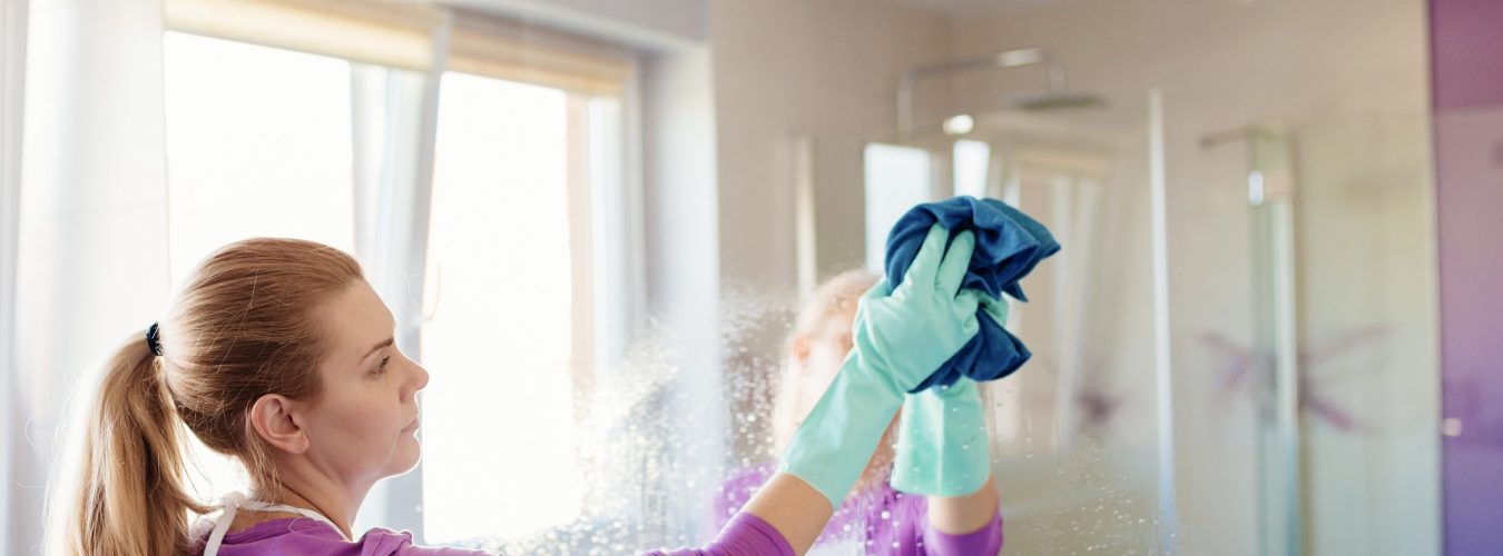 Young beautiful woman in cleaning mirror in bathroom