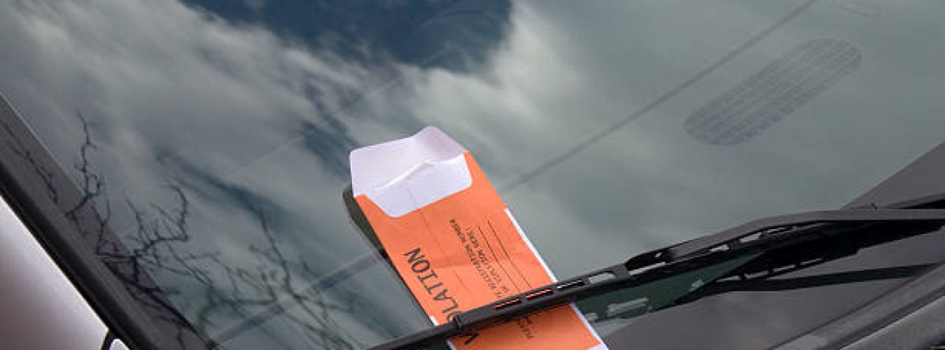 This image is of a car windshield with an orange parking ticket.