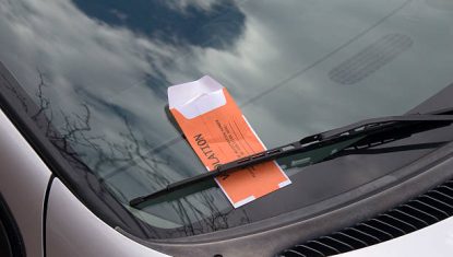 This image is of a car windshield with an orange parking ticket.