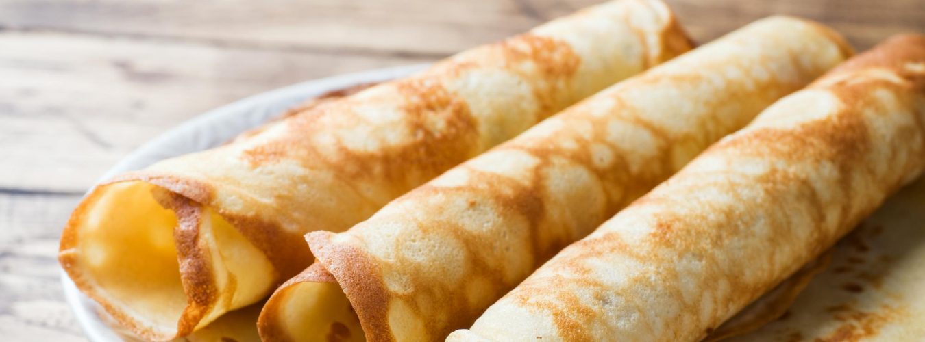 Thin pancakes on a plate. Wooden background. Close up.