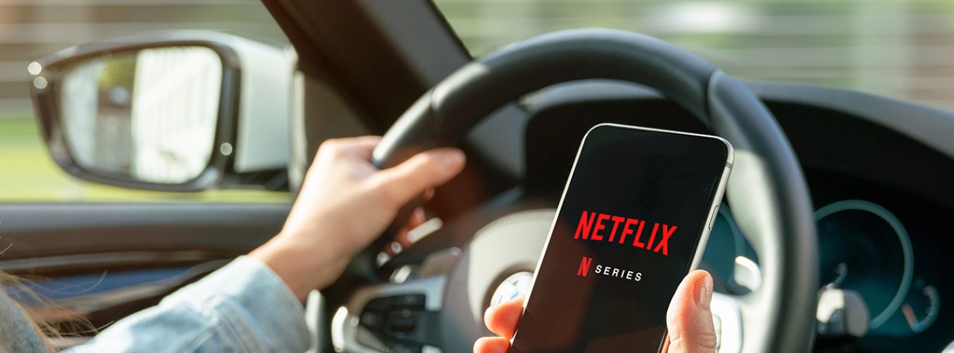 AACHEN, GERMANY – 31. August 2019 : Netflix app on Apple iPhone in car. Young man is browsing the movie video library what to watch.