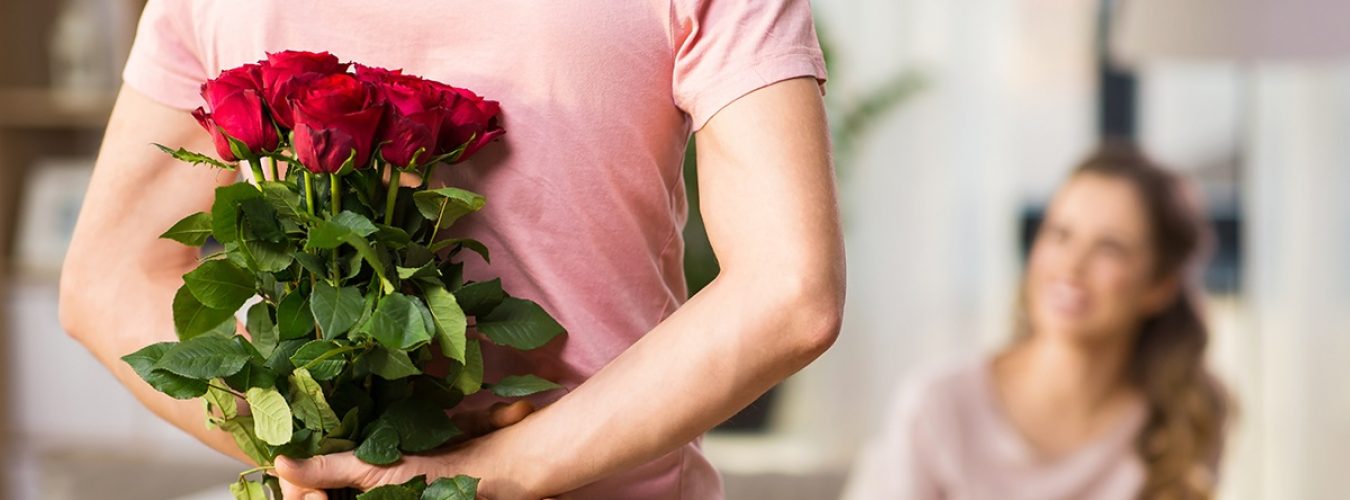 woman and man with bunch of roses behind his back