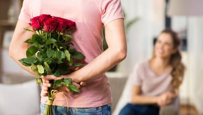woman and man with bunch of roses behind his back